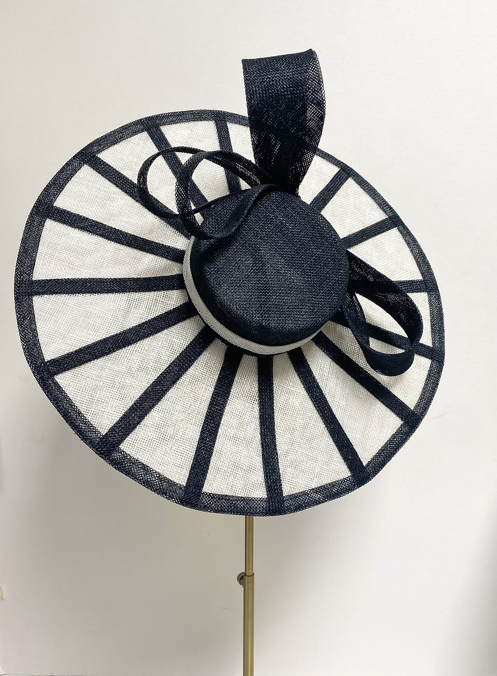 Thumbnail: A black and white sinamay wedding hat decorated with a black bow is displayed on a mannequin head