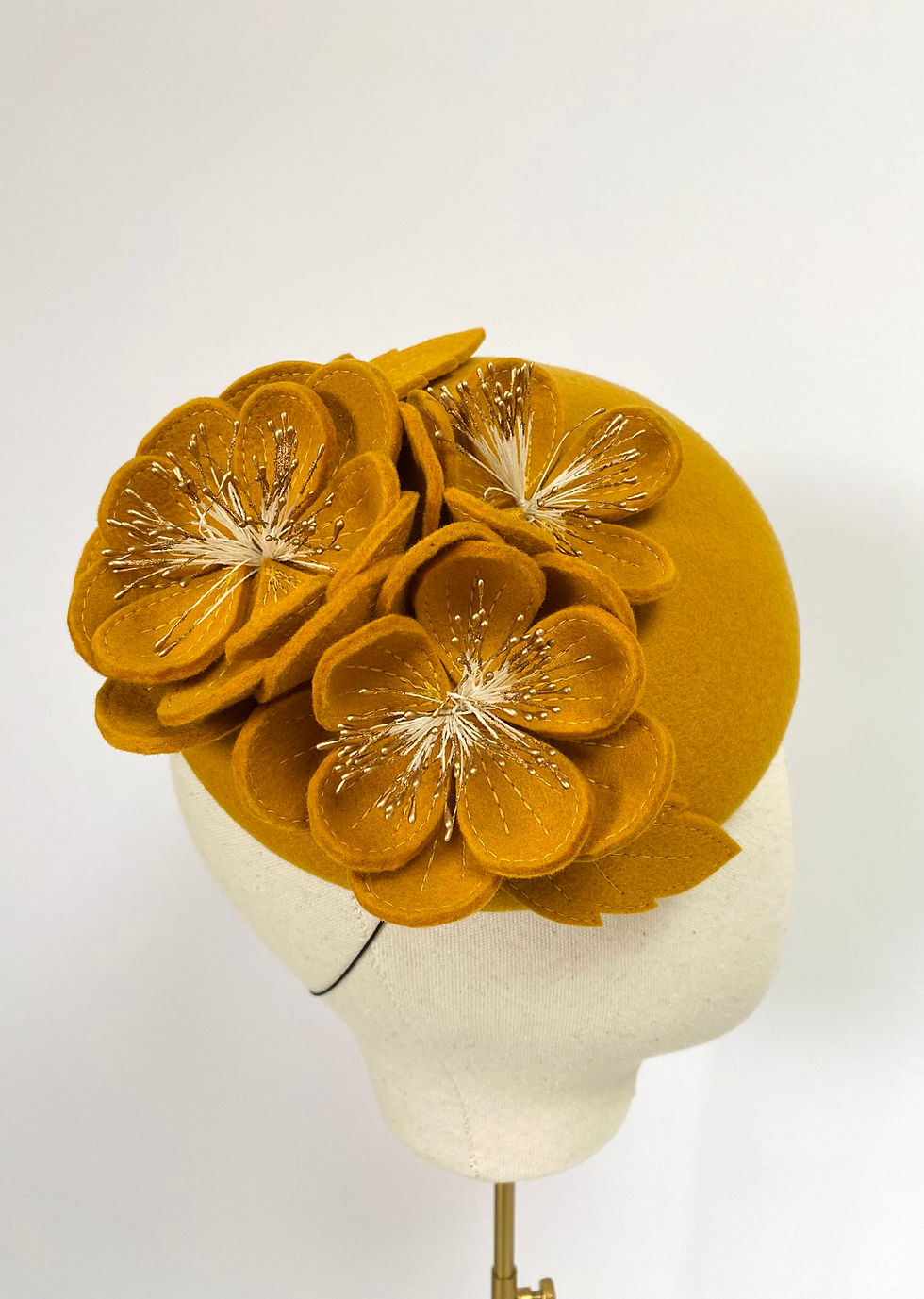 Thumbnail: A yellow felt wedding hat with matching flowers is displayed on a mannequin head