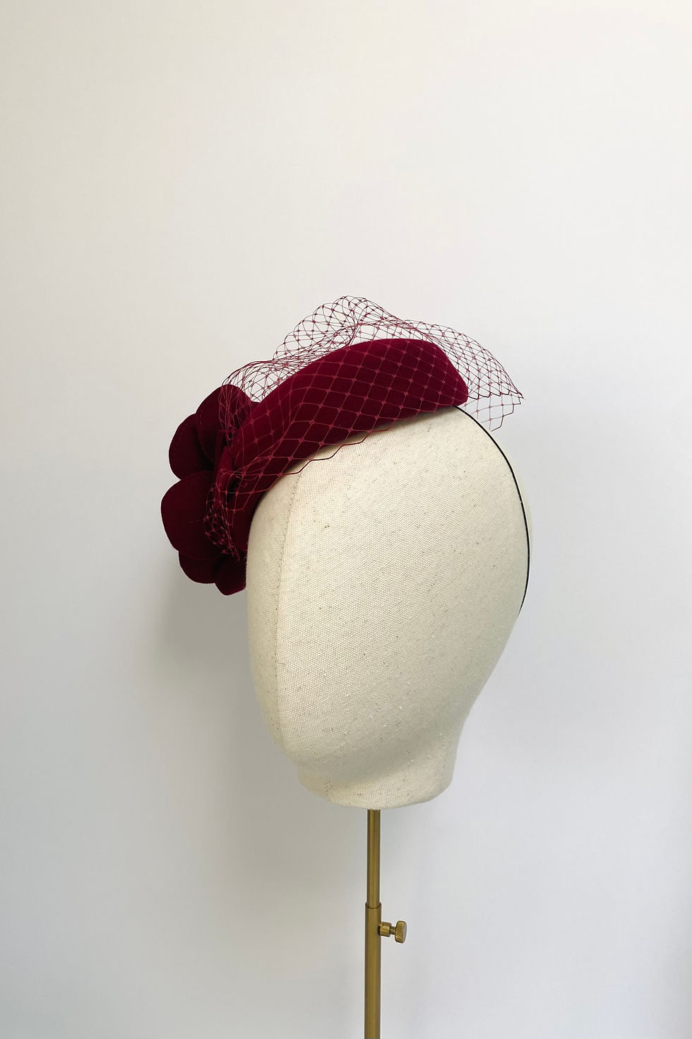 Thumbnail: A dark red felt flower wedding hat with a veil is displayed on a mannequin head