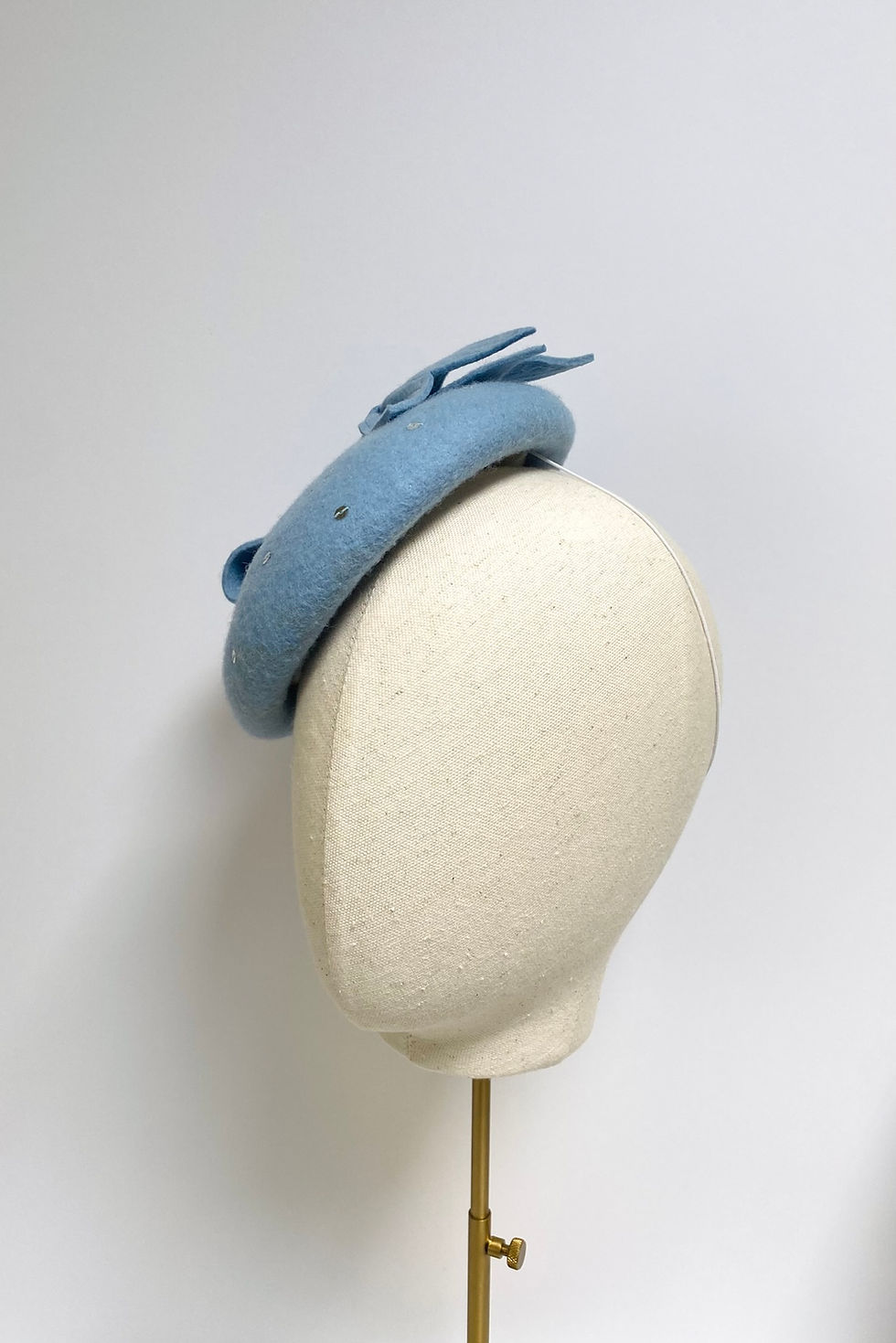 Thumbnail: A pale blue felt wedding hat with bow and silver sequins is displayed on a mannequin head