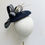 Thumbnail: A navy and ivory sinamay wedding hat with large striped bow and feathers id displayed on a mannequin head