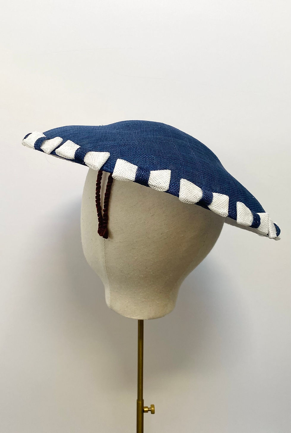 Thumbnail: A blue and white saucer hat with bows is displayed on a mannequin head