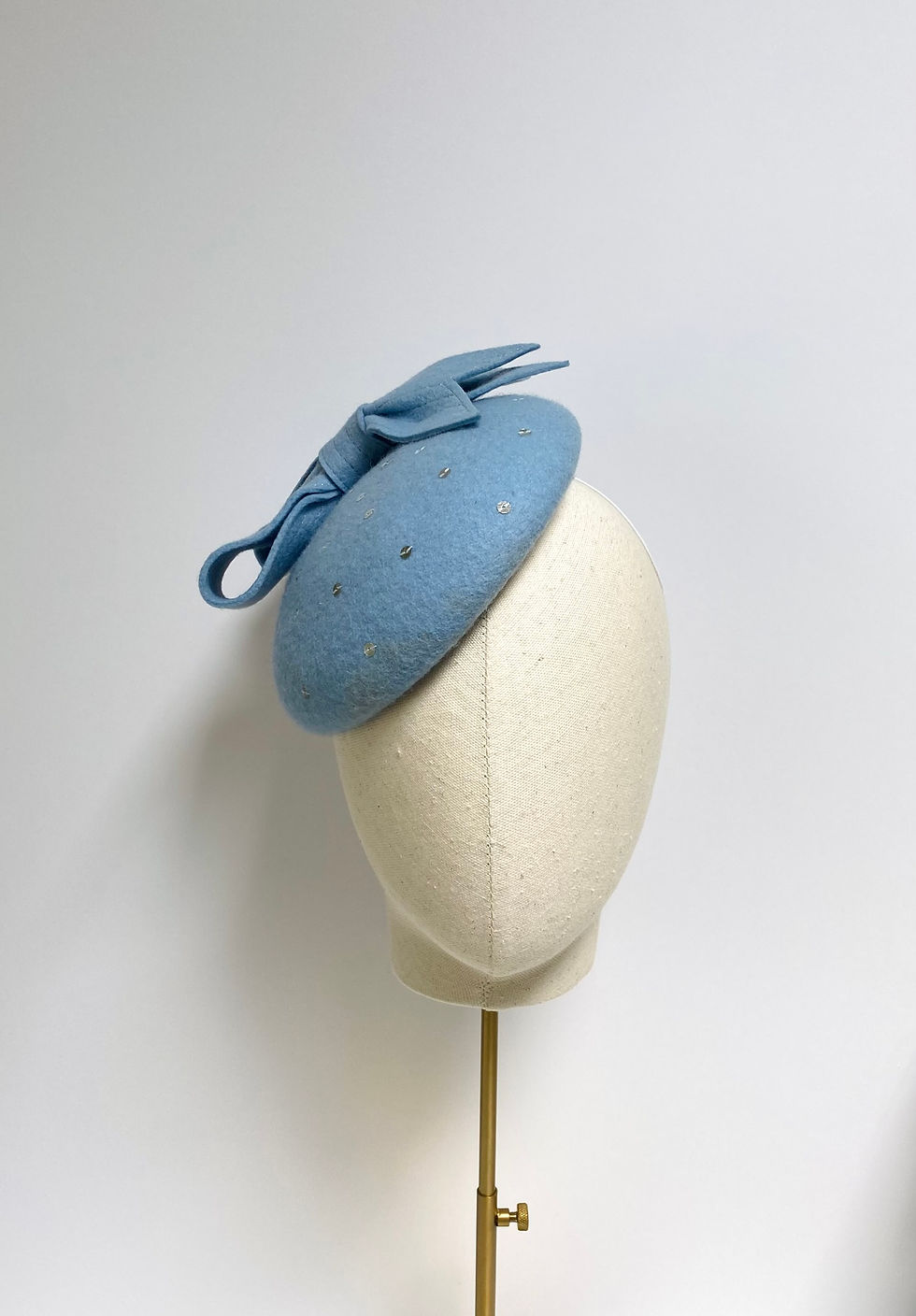 Thumbnail: A pale blue felt wedding hat with bow and silver sequins is displayed on a mannequin head