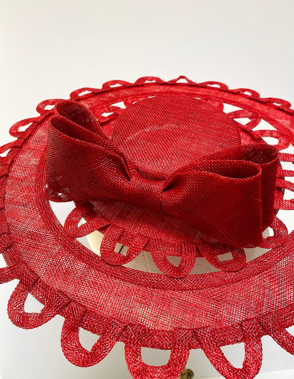 Thumbnail: A red boater hat with cut out detail and bow is displayed on a mannequin head