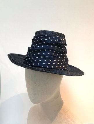 A navy hat with spotted fabric around the middle is displayed on a mannequin head.