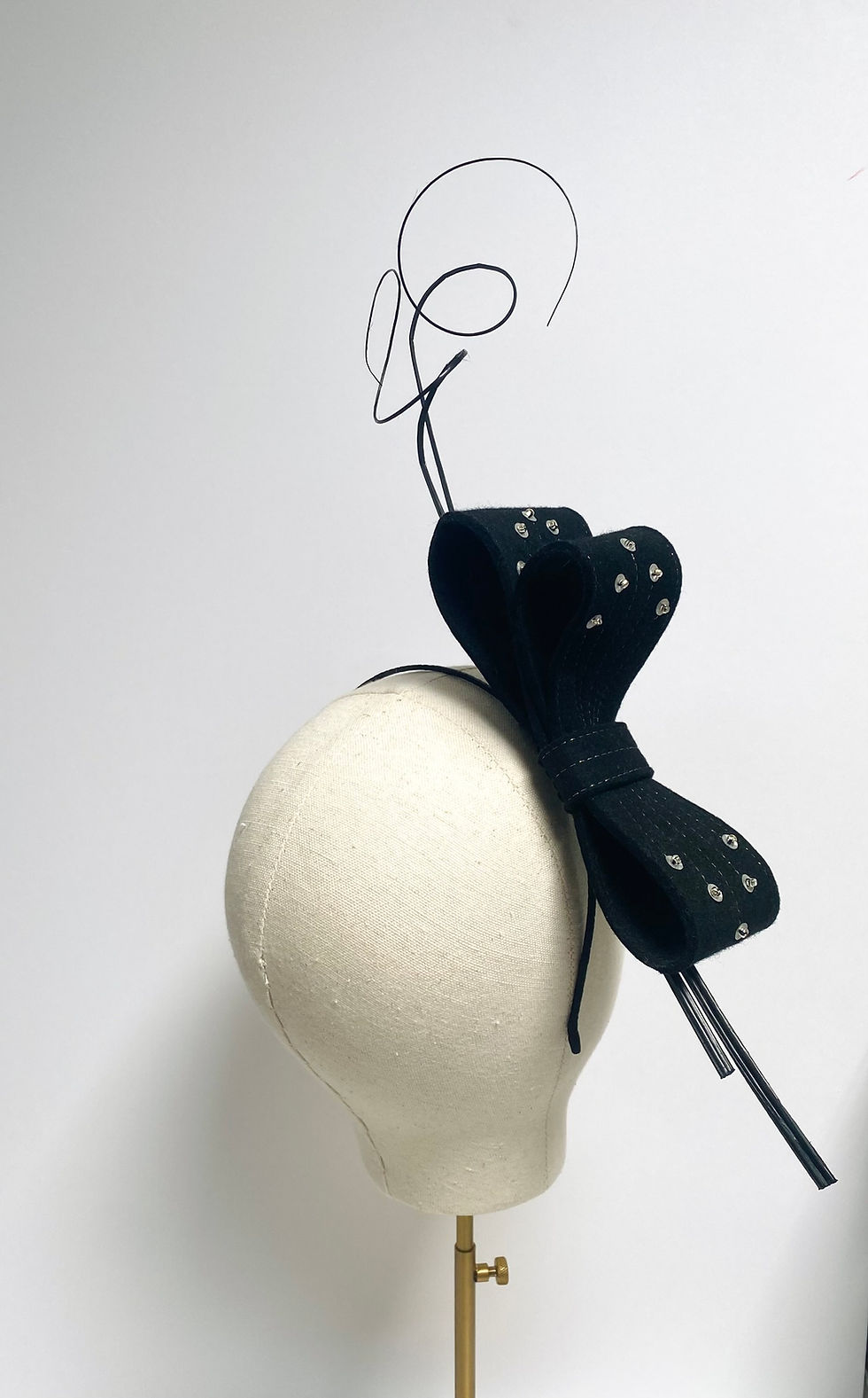 Thumbnail: A large black felt bow headband decorated with ostrich quill feathers and silver sequins is displayed on a mannequin head