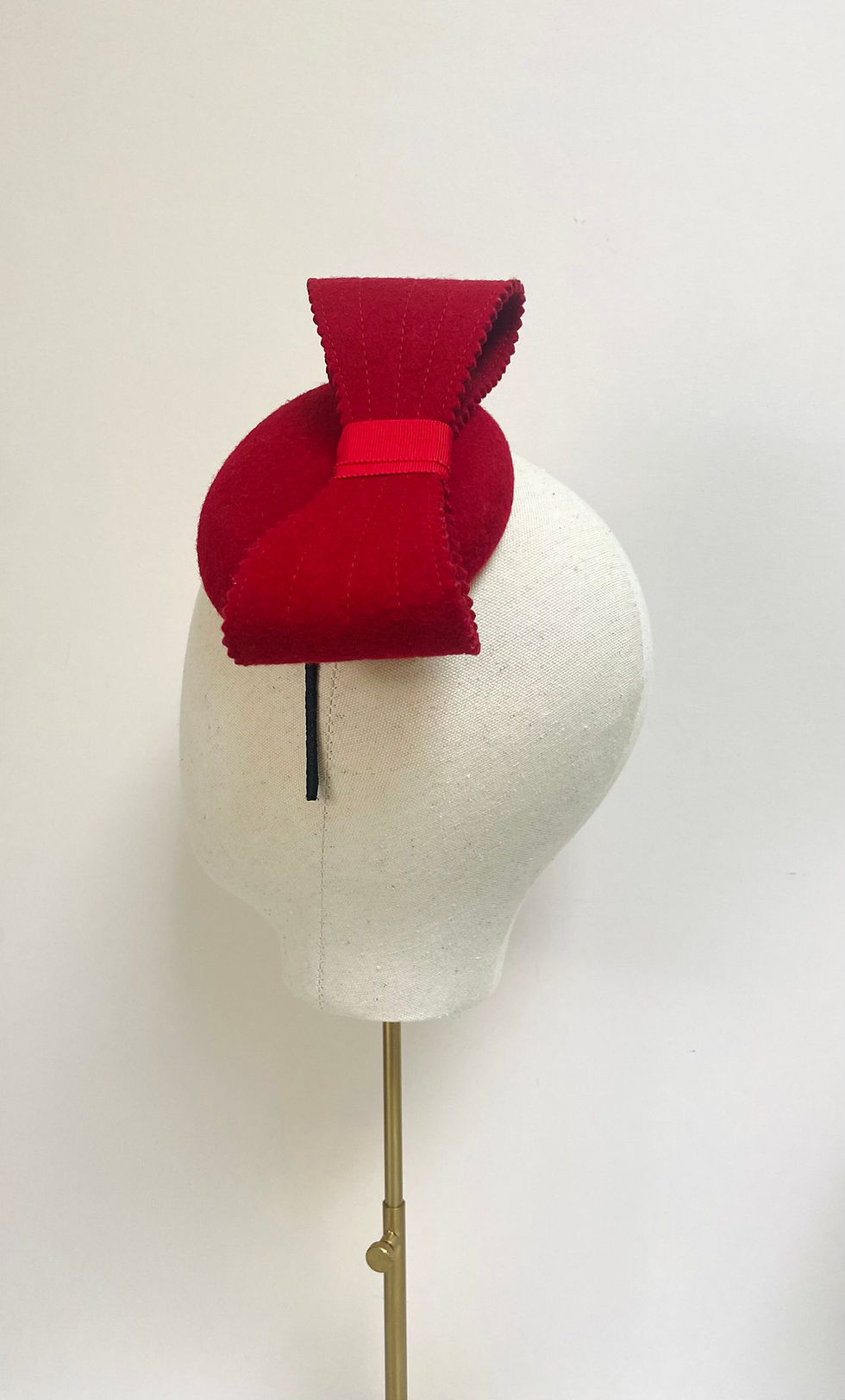 Thumbnail: A small red felt hat with matching bow is displayed on a mannequin head