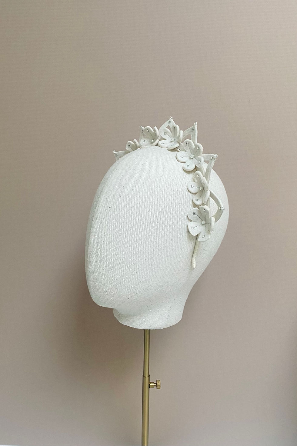 Thumbnail: A wedding bride crown created from ivory millinery felt and decorated with matching flowers is displayed on a mannequin head.
