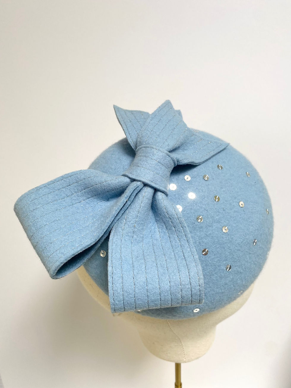 Thumbnail: A pale blue felt wedding hat with bow and silver sequins is displayed on a mannequin head