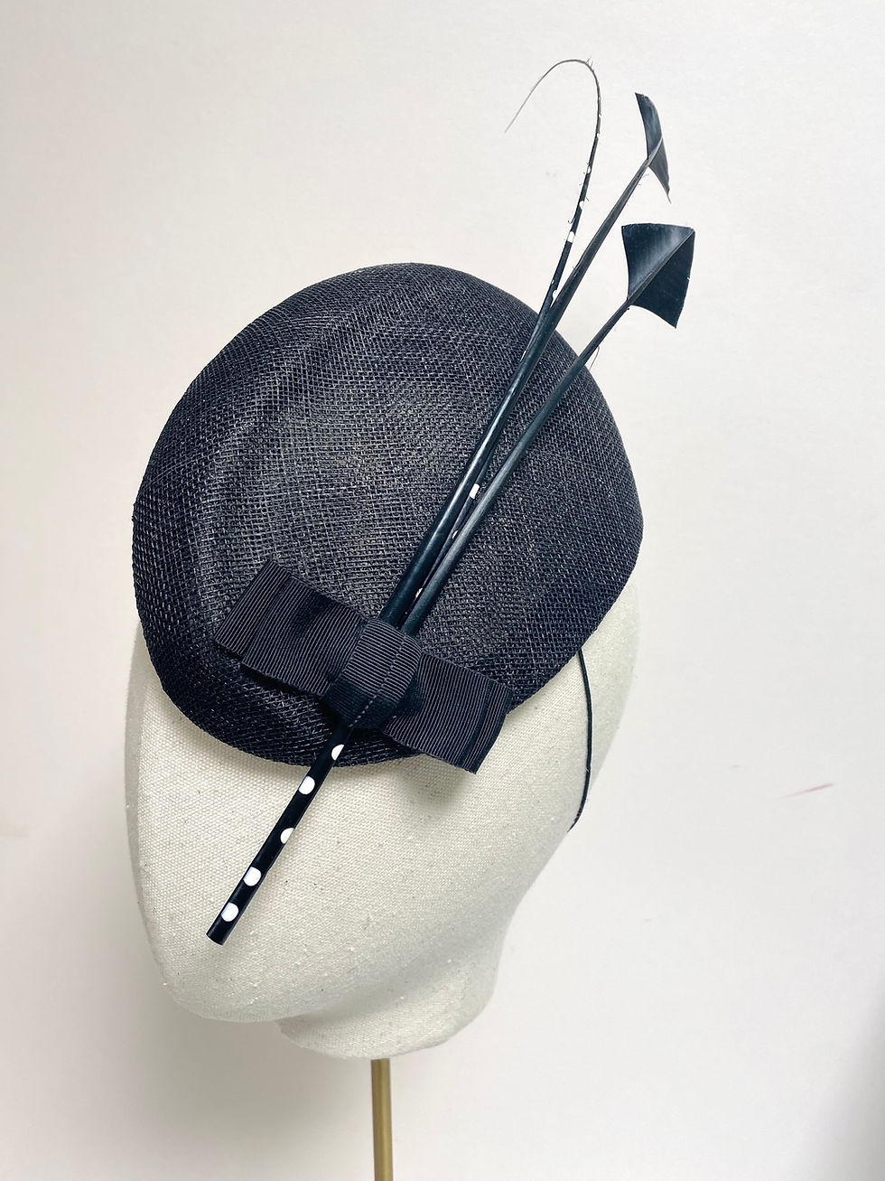 Thumbnail: A black fascinator hat with feathers is displayed on a mannequin head