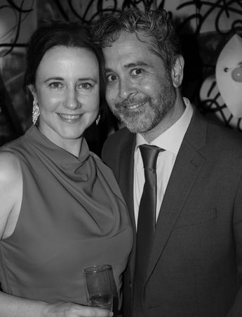 Black and white portrait of attractive couple smiling for the camera. The lady is holding a champagne glass.