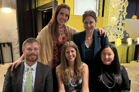 Group photo of 3 attorneys sitting down and two standing, smiling for the camera
