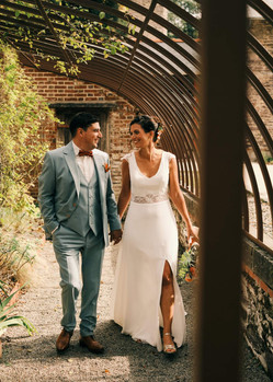 Bride and groom walking together under a garden arch