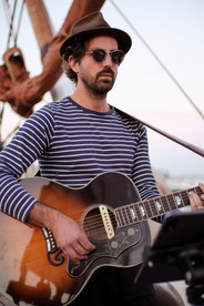 Live guitarist playing acoustic guitar during a sunset boat performance