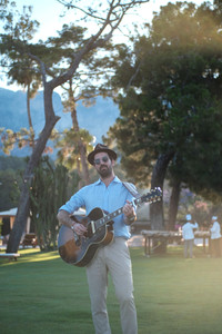 Acoustic guitarist performing on the lawn under trees