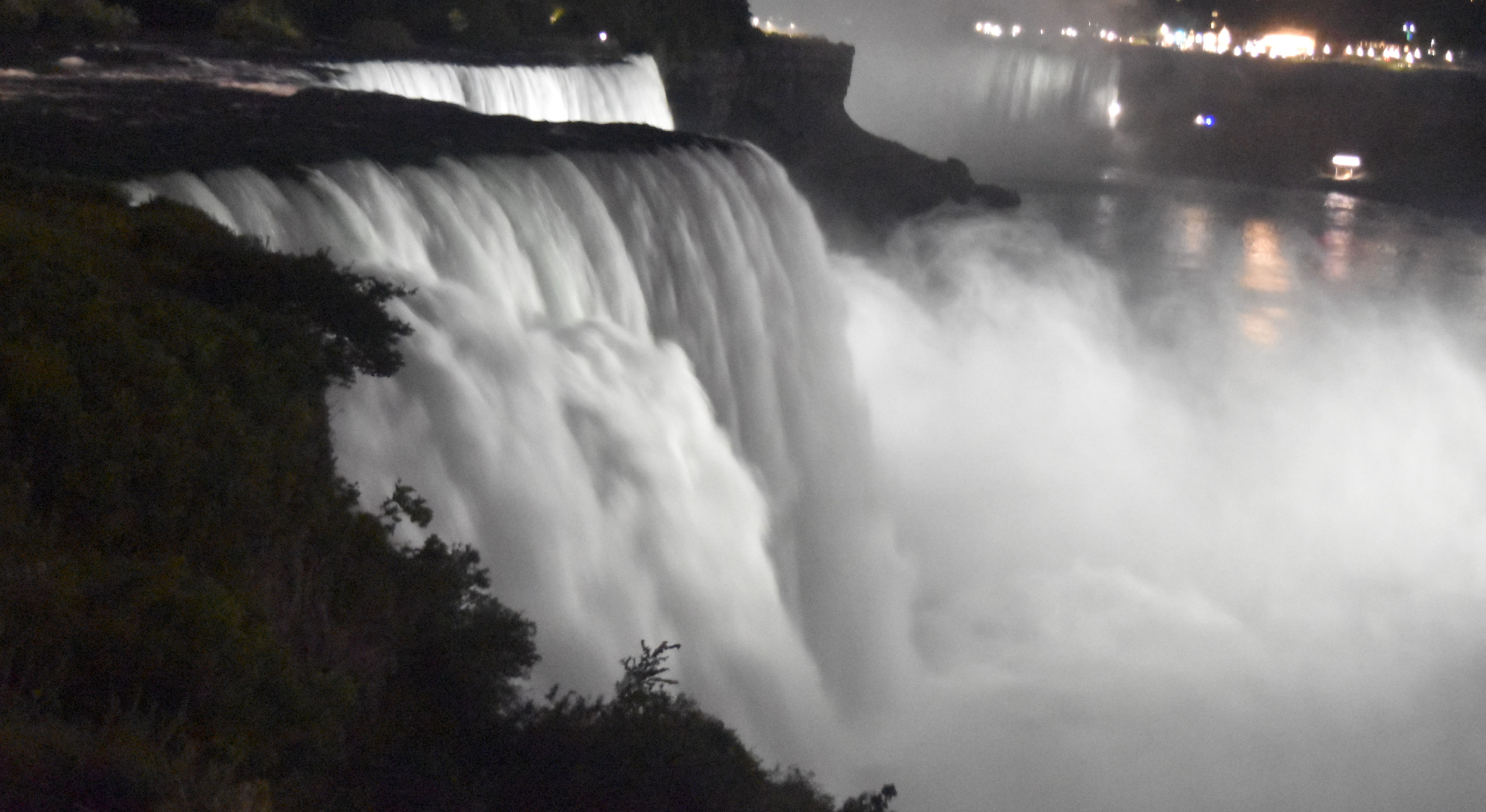 American Niagara Falls lit up at night, with Niagara Falls, ON in background
