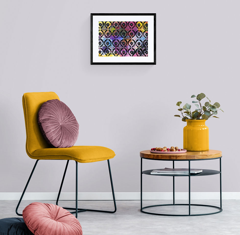 "11 Layers Of Love" by Jade Forder at Creative Abyss hanging insitu. In front is a padded bright yellow chair with a dusty rose cushion. On the floor is a pink and blue round cushion. There is a round wood and metal table with a yellow vase and leaves.