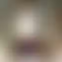 View through open reclaimed brass and glass doors to a bright back room with a magenta sofa, woven roman blind, and mid-century sideboard.