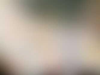 Close-up of a stainless steel overhead kitchen extractor fan mounted above a modern hob, set against a playful backsplash of bespoke, hand-painted tiles in colourful geometric and botanical motifs.