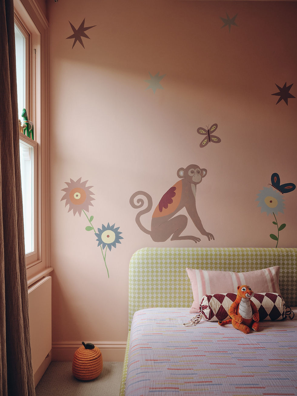 Peach children’s bedroom with a bespoke hand-painted monkey, flowers and butterflies mural, layered with colourful patterned furniture and textiles.