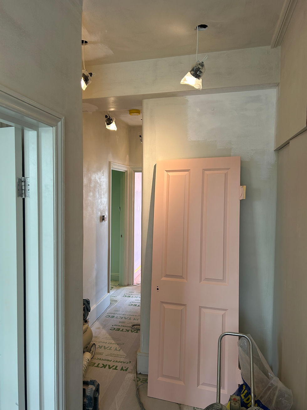 Soft sage green hallway during renovation with freshly painted walls, doors and ceiling awaiting completion. By Leo Wood at Kinder Design