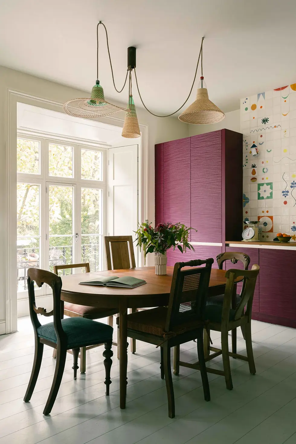 Dining area within a Victorian terrace kitchen renovation by Kinder Design featuring textured plum cabinetry, vintage dining chairs and sculptural pendant lighting.