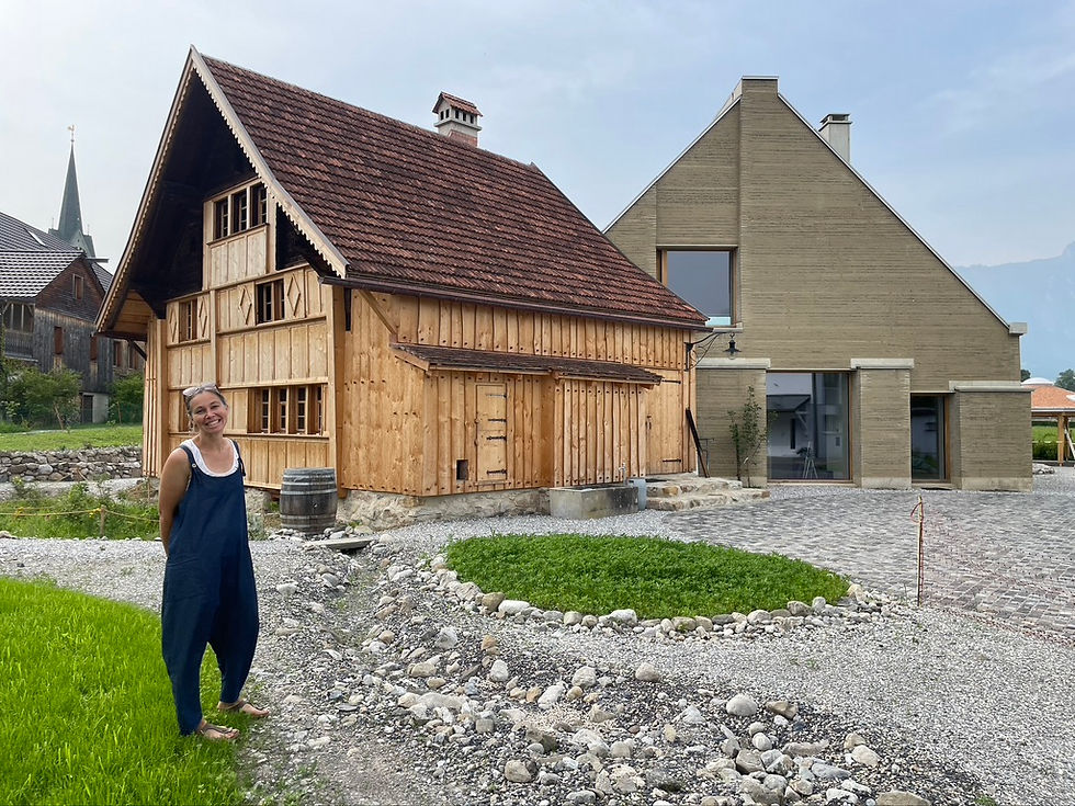 Isabelle Saluz, PK-Gestalterin und Initiantin des Projektes, neben dem Gässlihus und dem Anbau aus Stampflehm.