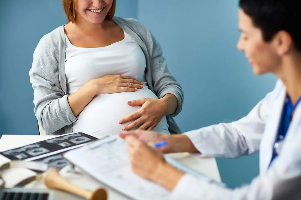 Pregnant woman smiling in a clinic while a doctor reviews ultrasound images and notes at a desk, calm and reassuring.