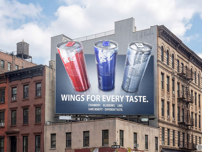 Billboard mockup by Brandspace3D integrated onto a city building, displaying a 3D product render for Red Bull's Red, Blue, and Silver editions to demonstrate hyper-realistic Out-of-Home (OOH) digital twin advertising.