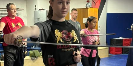 Group of children holding certificates and awards at martial arts studio.