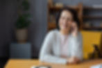A woman with dark hair wearing a light gray sweater smiles as she talks on the phone about her favorite things.
