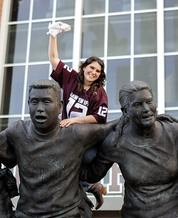 Texas A&M Senior twirling a Texas A&M Towel on the 12th man statue