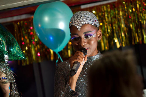 performer on stage with an eclectic head piece and a microphone singing