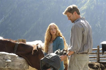a woman and a man in the mountains with horses