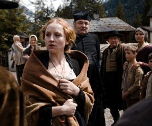 A woman with a blanket wrapped around her shoulders with people standing behind her