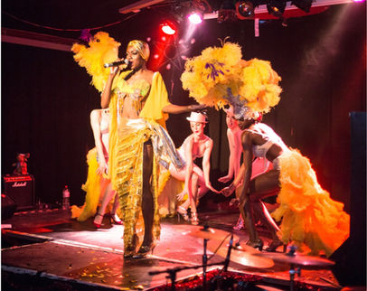 Female performers on stage in opulent yellow costume with feathers