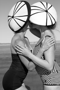 two women with retro hats and bathing suits hugging each other at the beach