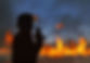 Firefighter silhouette communicating on radio as wildland fire rages behind them.