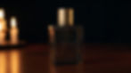 Flacon de parfum Heritage posé sur une table en bois, éclairage aux bougies