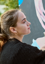 Woman painting a large portrait with a brush