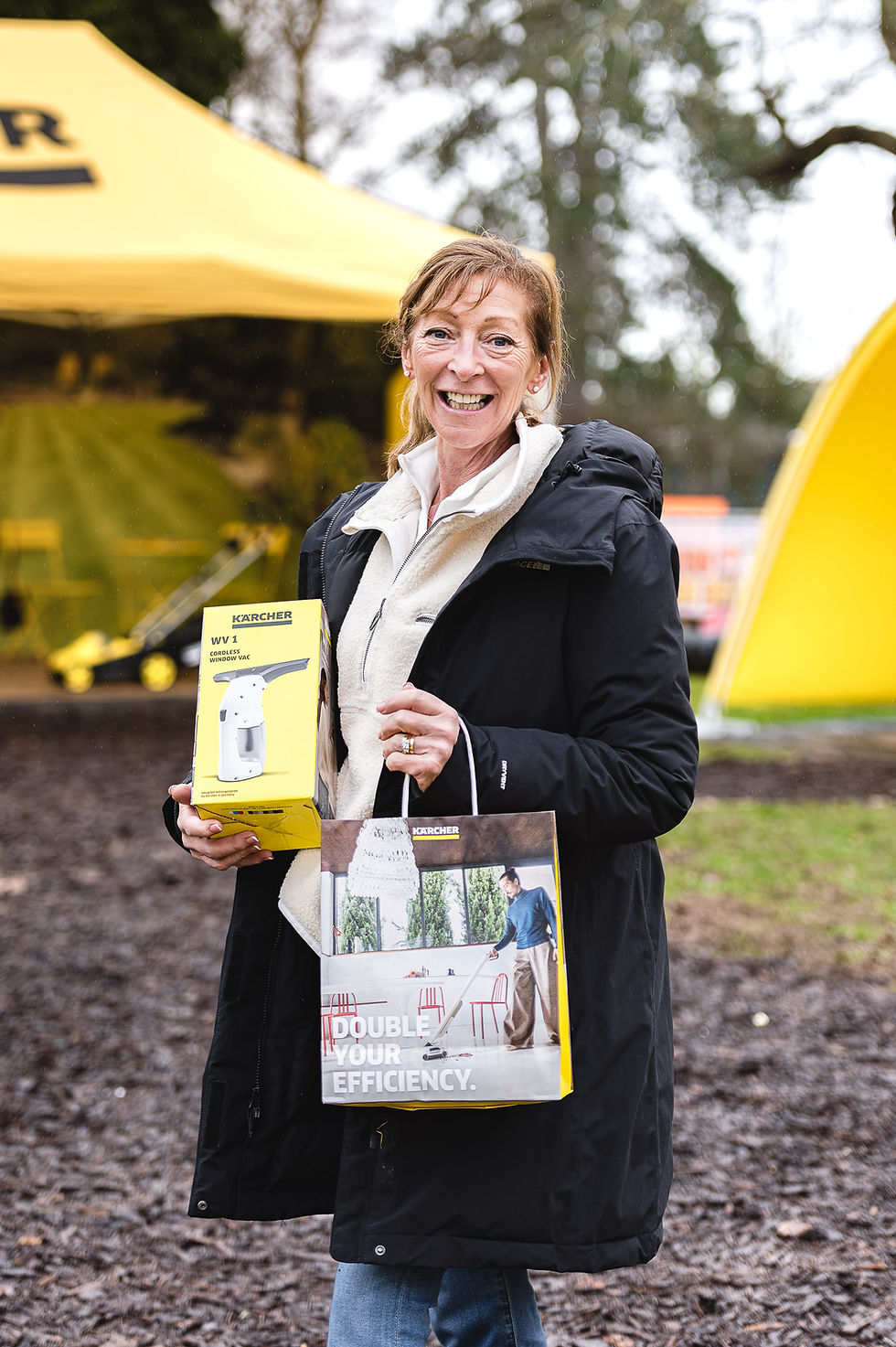 Guest holding a Kärcher product prize and branded bag at Woodland Grange
