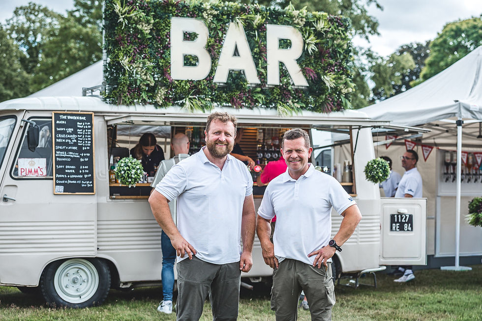 Two members of the Vanderbar team standing in front of their mobile bar at Himley Hall