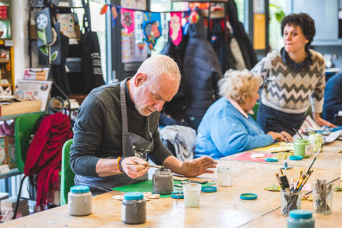 Participant painting at a community arts workshop table in London