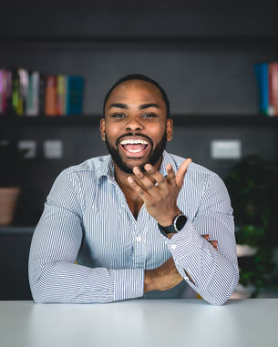 A business man, leans forward confidently and laughs looking directly into camera.  Captured by Birmingham headshot photographer Aaron Scott Richards