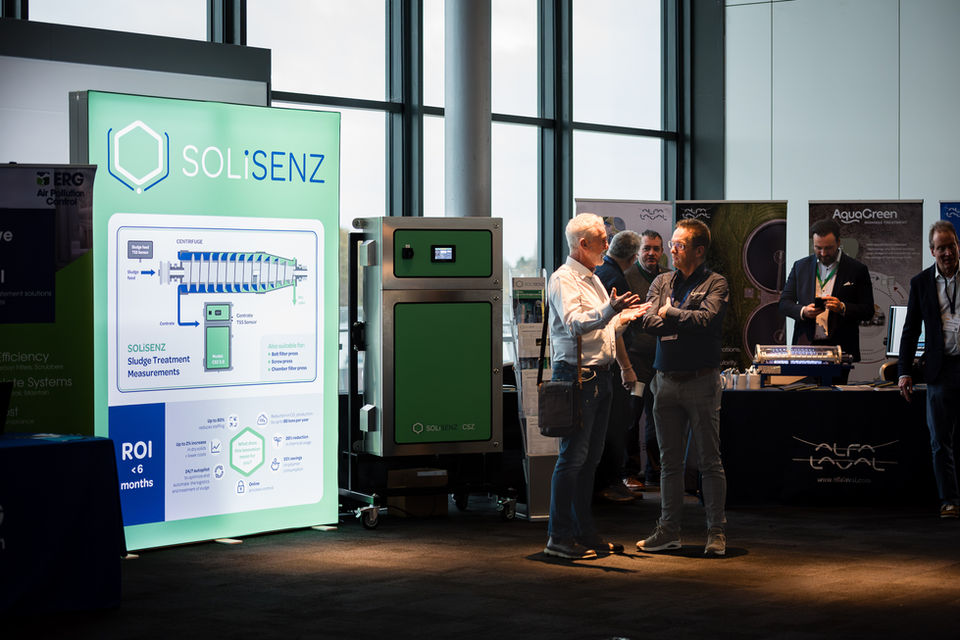 Wide shot of an exhibition hall with branded stands and delegates networking, event photography