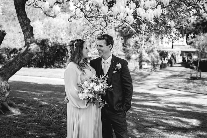 Black and white couple portrait under a flowering tree, bride holding bouquet