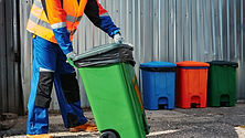 male-janitor-uniform-cleans-trash-can-street.jpg