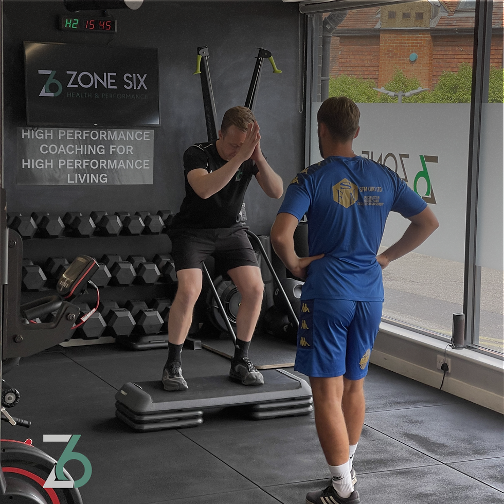 Physiotherapist supervising a man performing step-ups on a platform in a Zone Six gym.