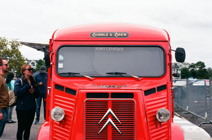 Front view of a bright red vintage Citroën truck labeled "Bubble & Brew," parked with people gathered beside it.