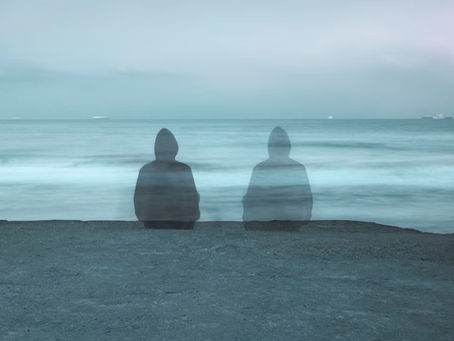 Una persona de espaldas sola sentada frente al mar